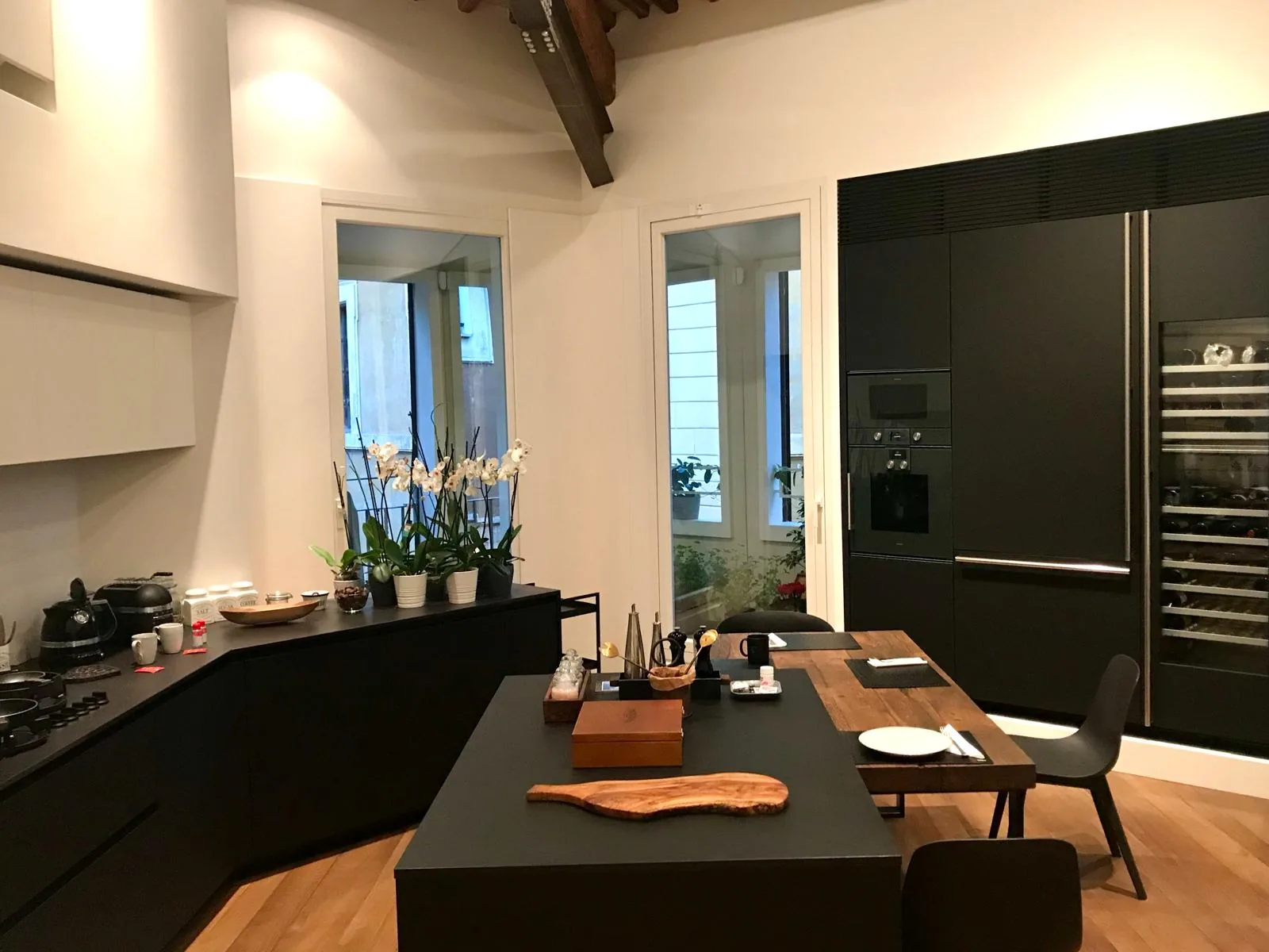 Cucina ultimata con mobili neri, travi lignee e tavolo in legno