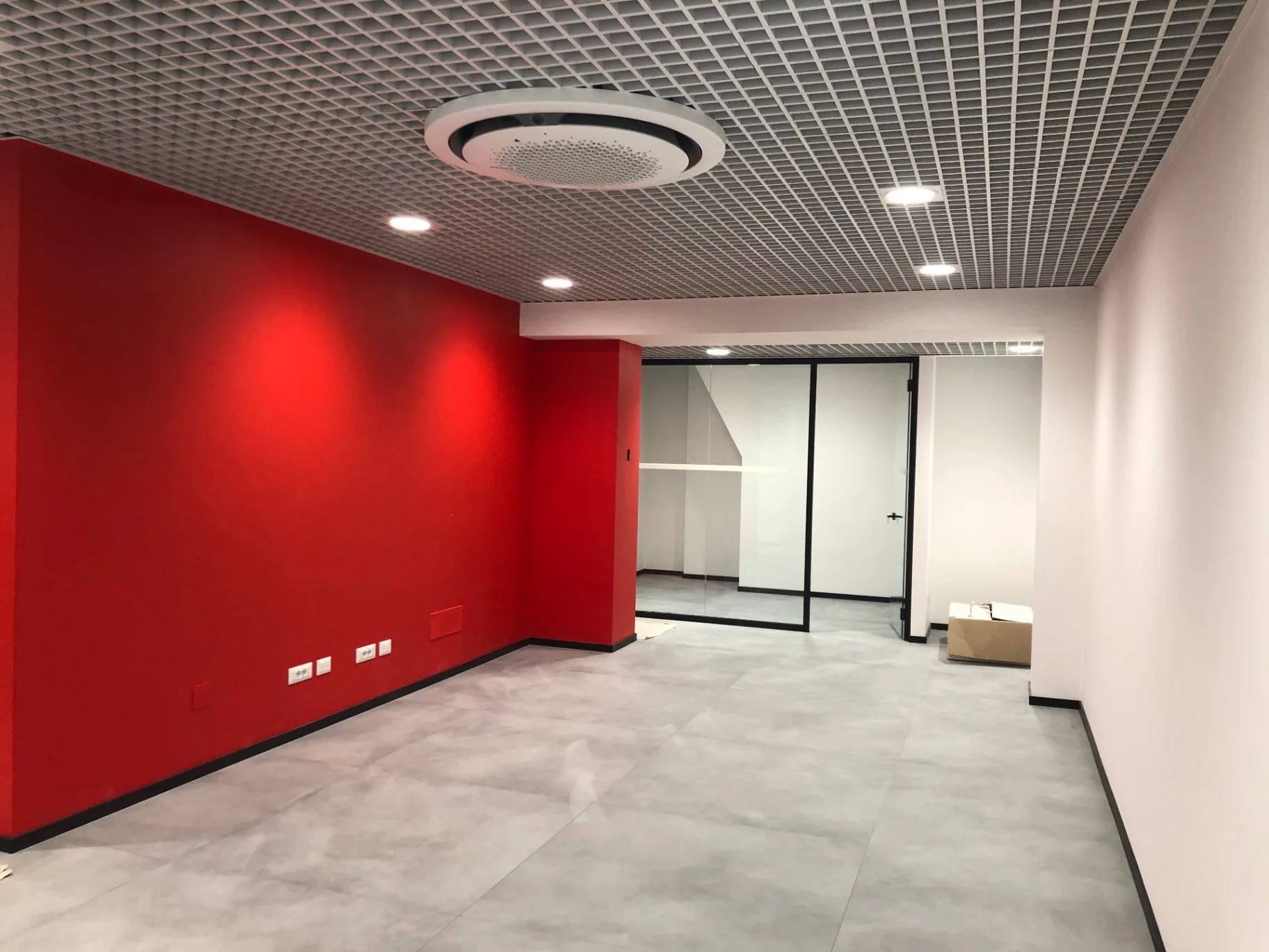 Ambiente uffici completato con parete rossa, controsoffitto grigliato e diffusore circolare