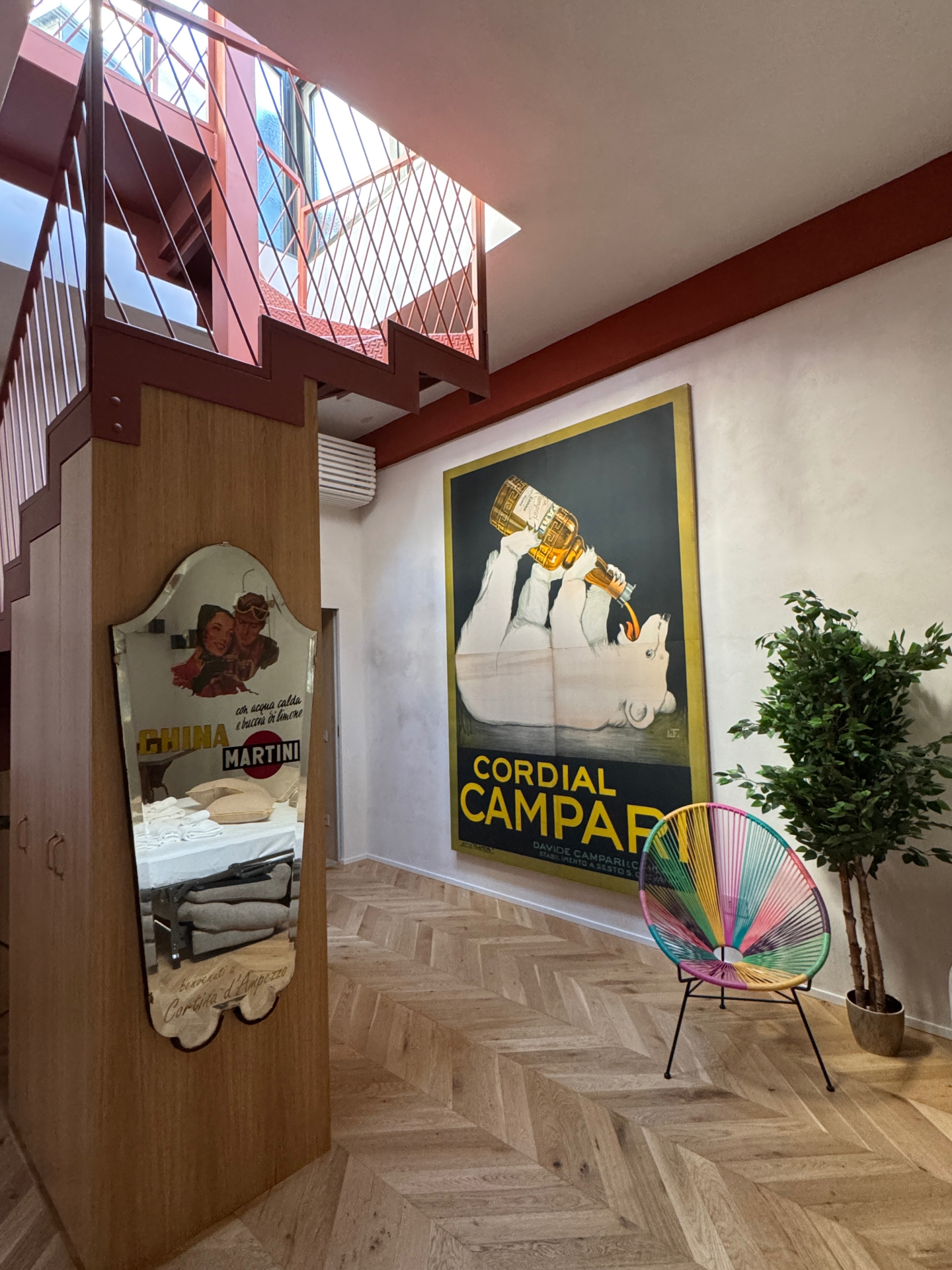 Interno con scala in ferro rosso, parquet a spina e boiserie in legno
