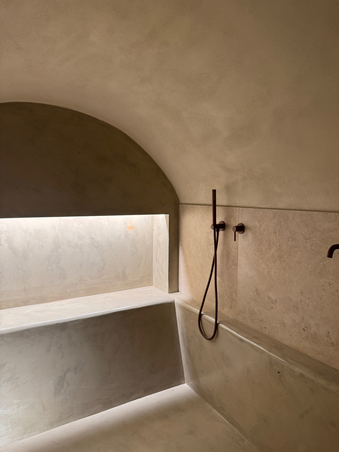 Ambiente bagno voltato in microcemento con nicchia illuminata