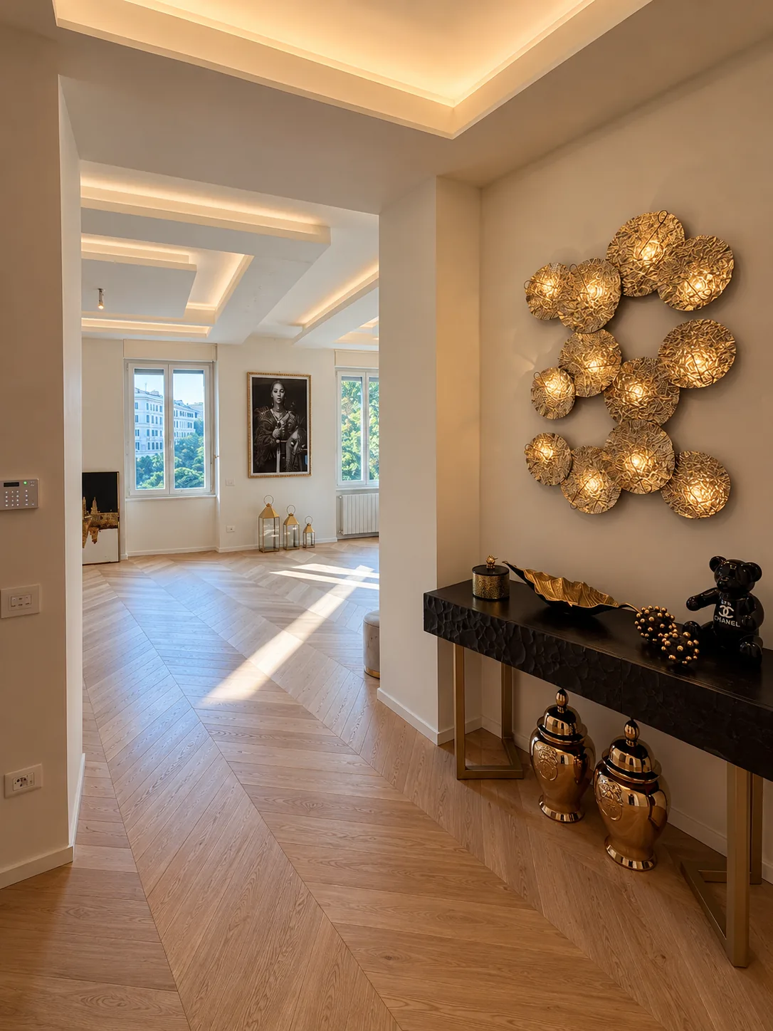 Ingresso e zona giorno con parquet a spina, controsoffitti con luce integrata e applique decorativa