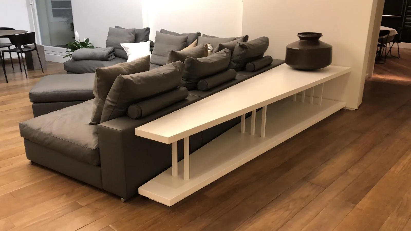 Soggiorno ultimato con divani grigi, mobile bianco e pavimento in legno