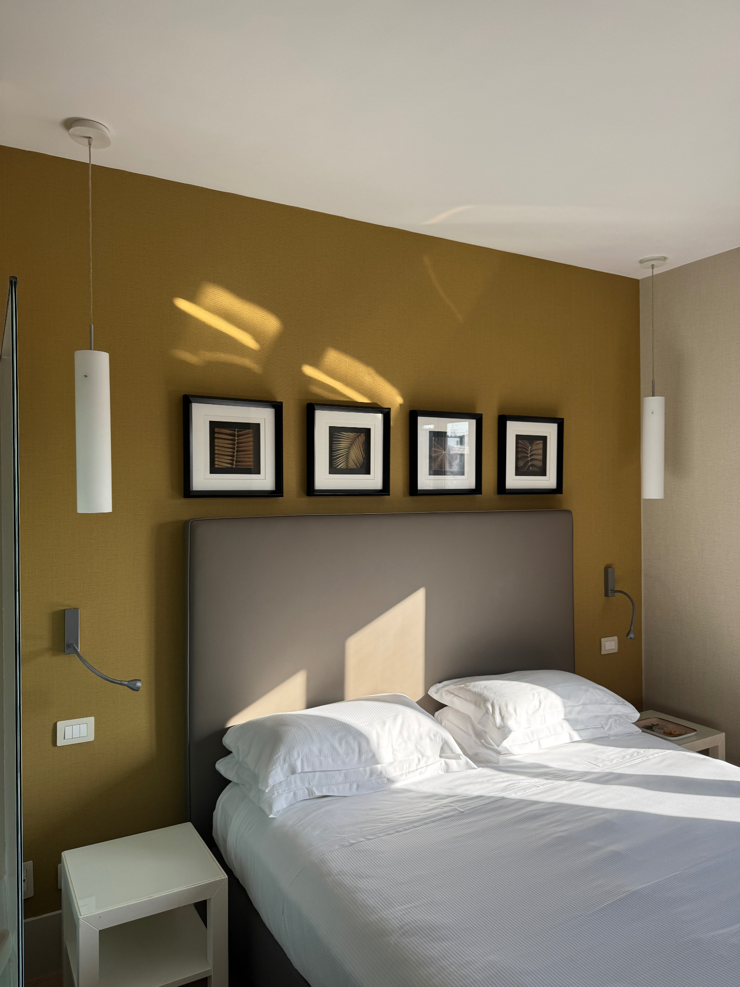 Camera con parete ocra, testata imbottita e luce naturale